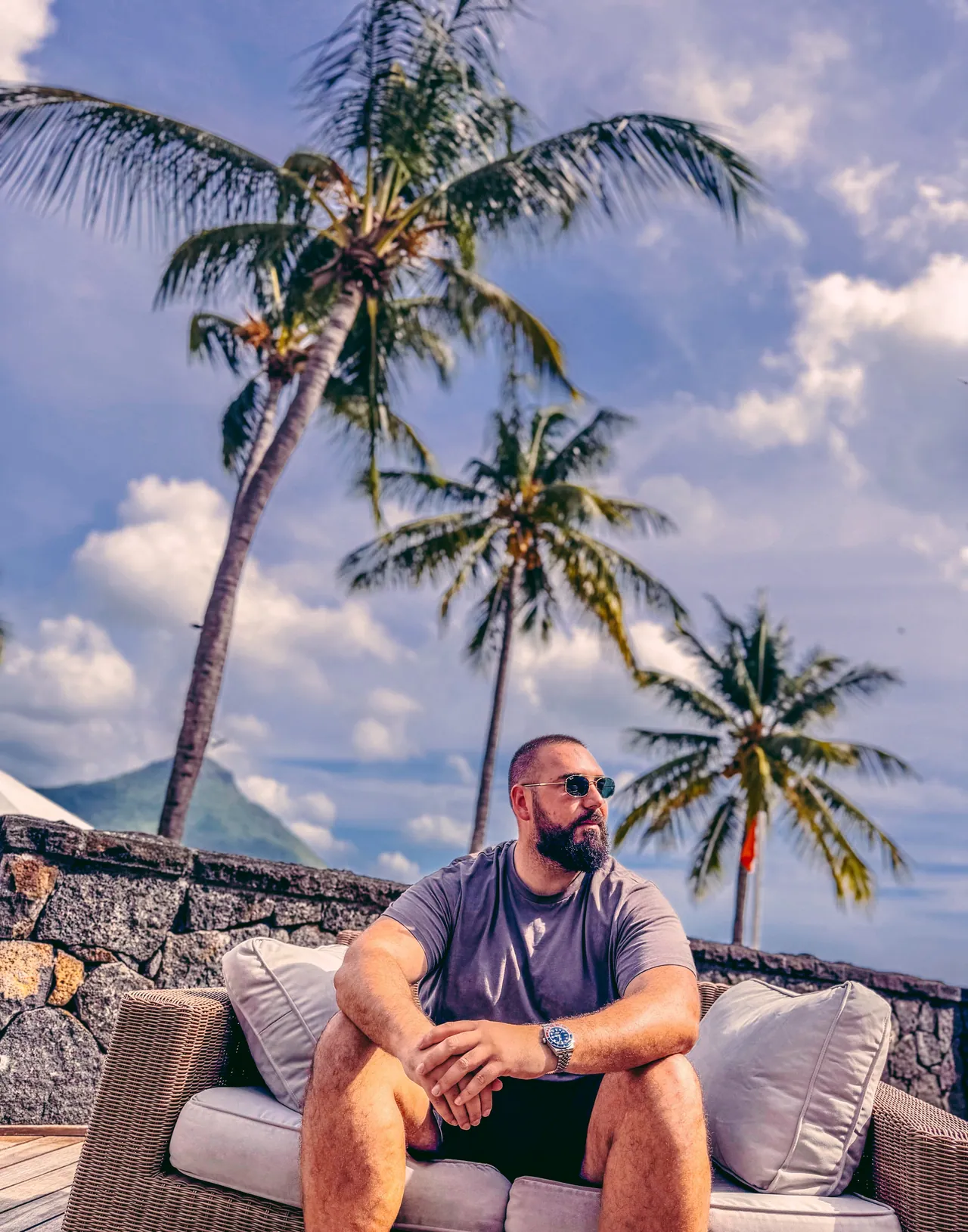 Billy seated outdoors beneath palm trees.