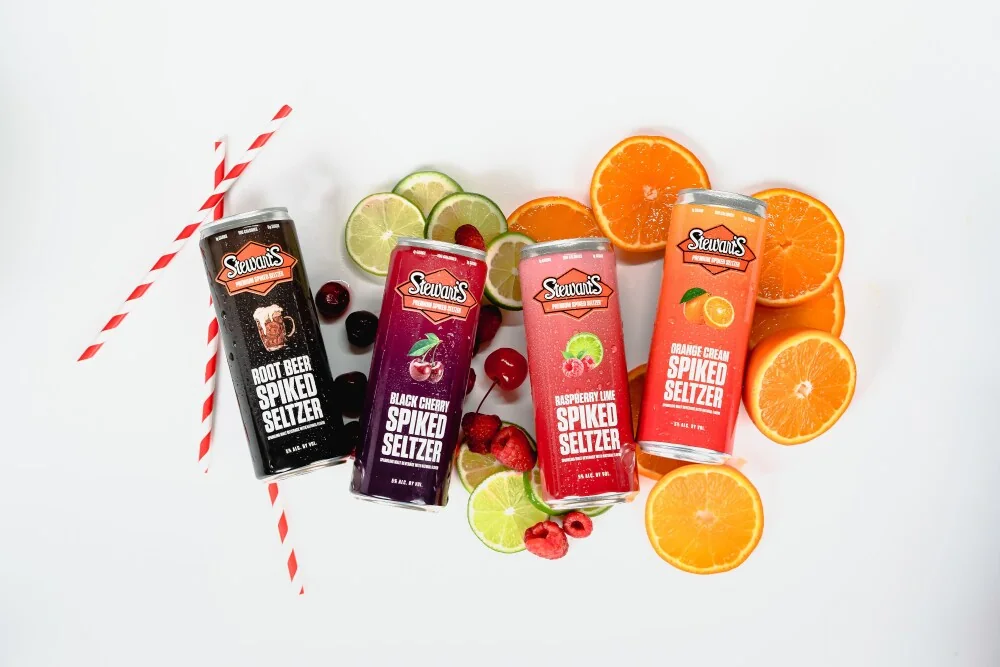 Stewart’s Spiked Seltzer flavor lineup arranged with orange, cherry, lime and berries