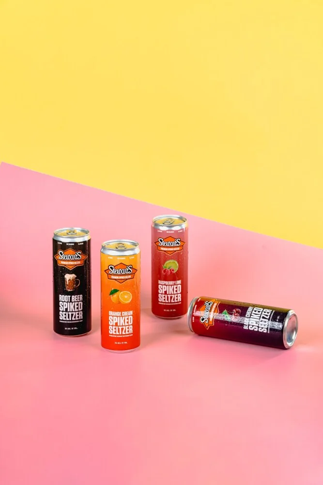 Stewart’s Spiked Seltzer cans on a diagonal yellow and pink studio background